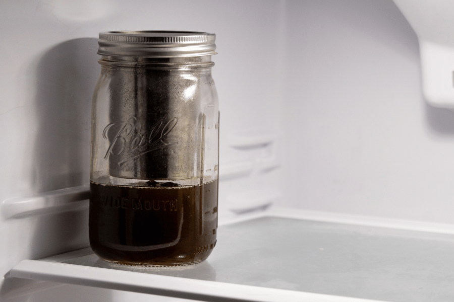 A mason jar of freshly infused cannabis oil cooling inside a refrigerator