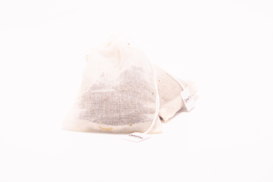 Used cannabis pulp inside a mesh tea bag, prepared for reuse as a DIY bath soak or compostable pouch.