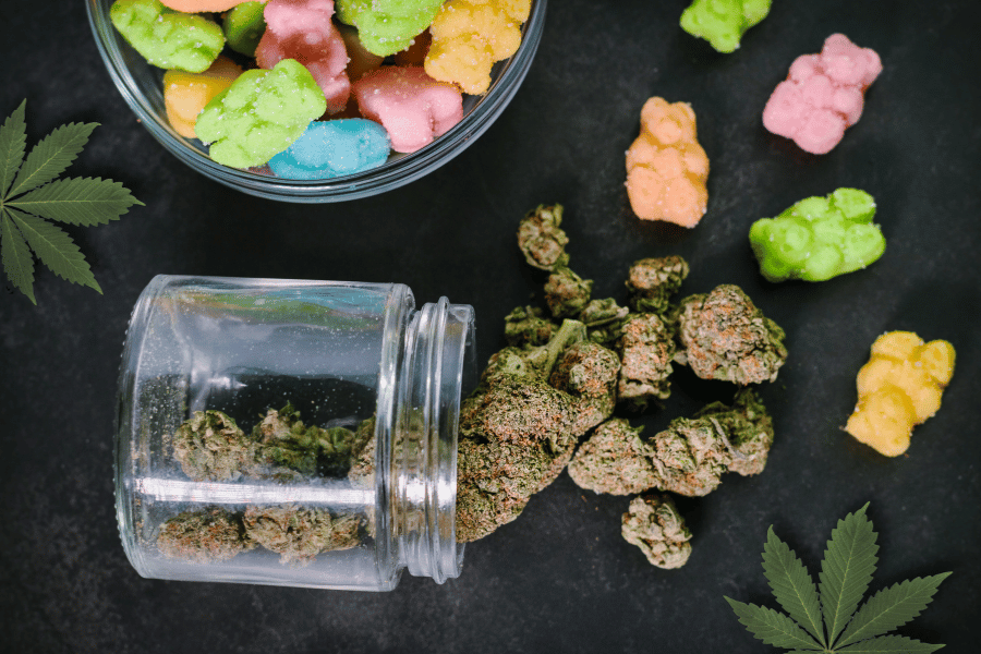Jar of cannabis buds beside edible gummies showing the difference between decarboxylation and oil infusion processes